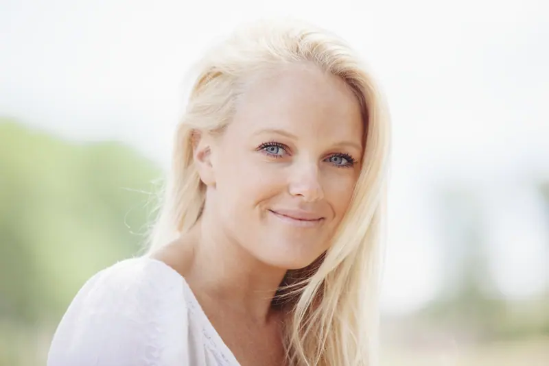 Beautiful blond woman smiling in soft outdoor ligh