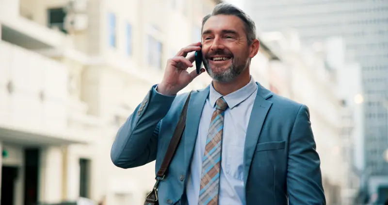 Smiling man in suit talking on phone outside